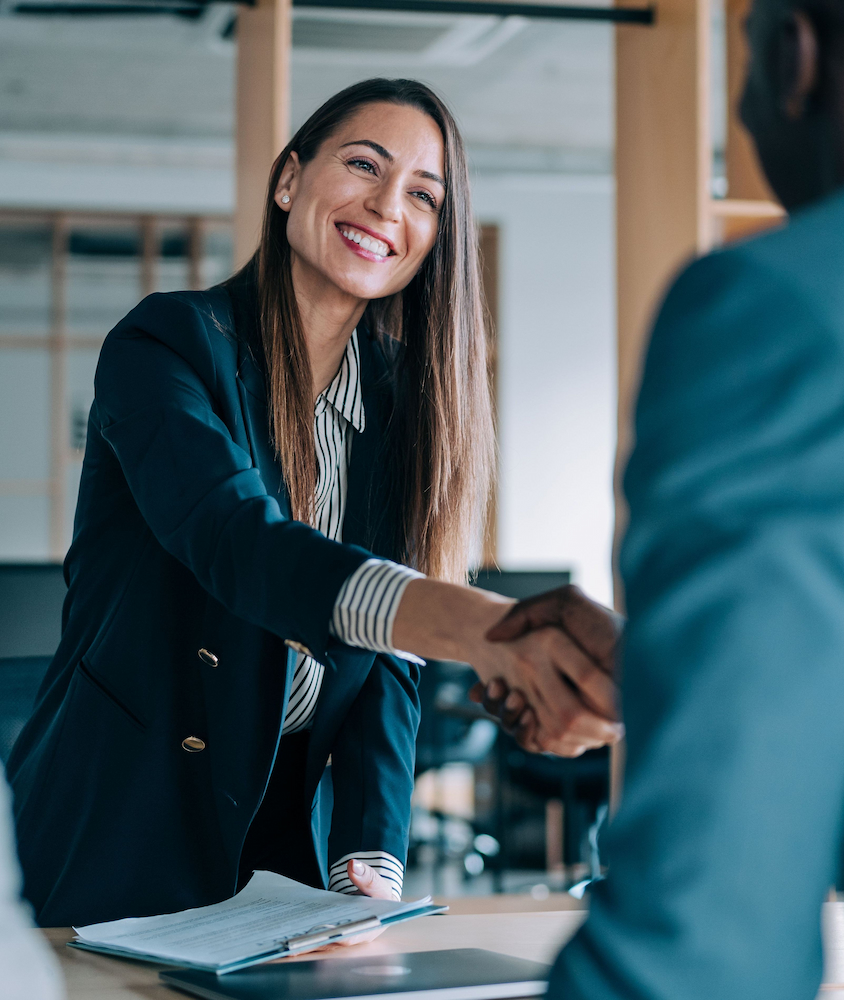 Two professionals shaking hands across a conference table